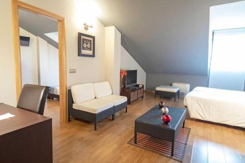a bedroom with a bed and a living room at Hotel El Tratado in Tordesillas