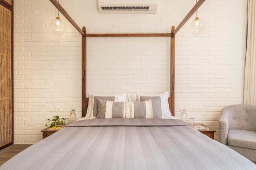 a bedroom with a bed and a chair at La Zamora, 3BHK Villas near Vagator & Anjuna Beach, North Goa with Private Pool, Garden, Terrace & Security in Assagao