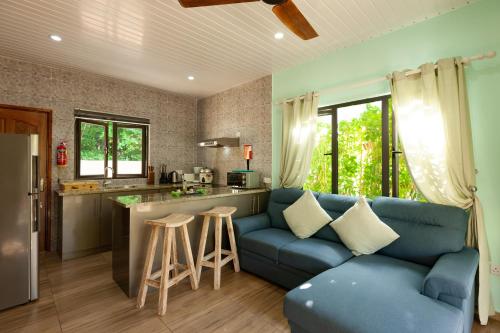 a living room with a blue couch and a kitchen at Casa De Leela Self Catering Guest House in La Digue