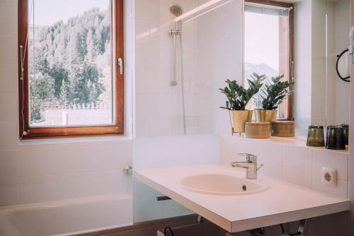 a bathroom with a sink and a tub and a window at Apartment Mohnenfluh in Schröcken