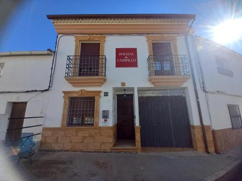 - un bâtiment blanc avec une porte et un panneau dans l'établissement Posada de Campillo, à Campillo de Altobuey