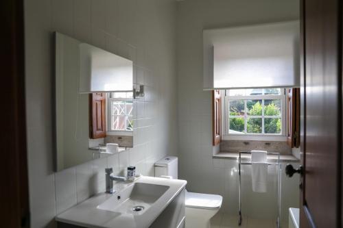 a white bathroom with a sink and a window at Quinta do Candeeira in Santa Maria Da Feira