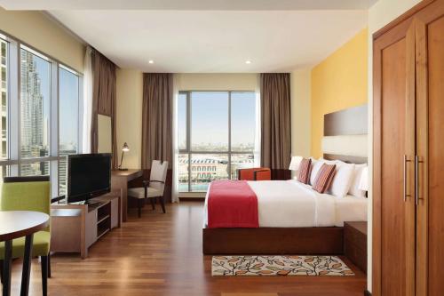 a hotel room with a bed and a desk and a television at Ramada by Wyndham Downtown Dubai in Dubai