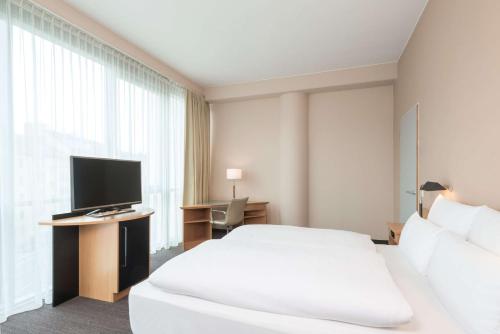 a hotel room with a large bed and a television at NH Düsseldorf City in Düsseldorf