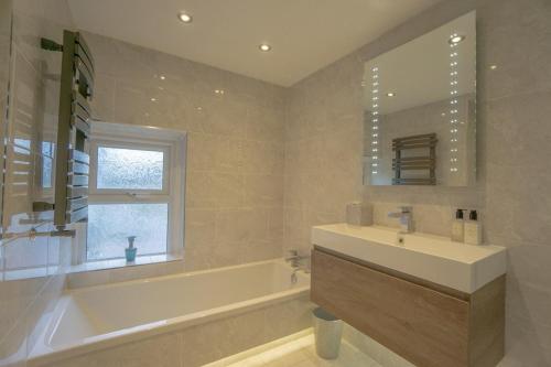a bathroom with a tub and a sink and a mirror at Mairannedd in Abersoch