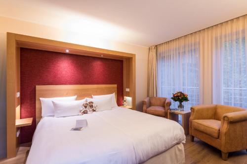 a hotel room with a large bed and two chairs at BollAnts Spa im Park in Bad Sobernheim