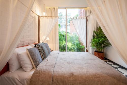 a bedroom with a large bed with a window at La Zamora, 3BHK Villas near Vagator & Anjuna Beach, North Goa with Private Pool, Garden, Terrace & Security in Assagao