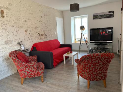 a living room with a red couch and two chairs at Gîte du Parc des Mauves in Meung-sur-Loire