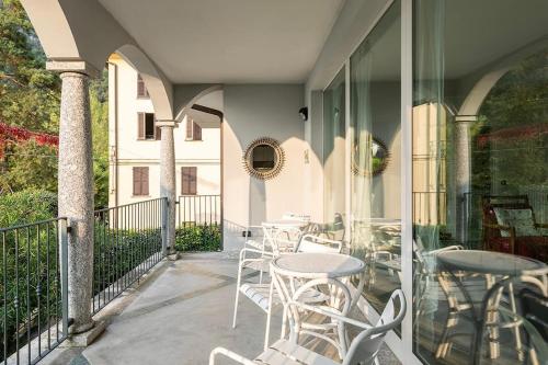 a patio with tables and chairs on a balcony at Villa Elisabeth in Lierna