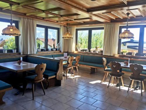 un restaurante con mesas, sillas y ventanas en Pension Heidelberg - Fam Fuchs, en Hopfgarten im Brixental