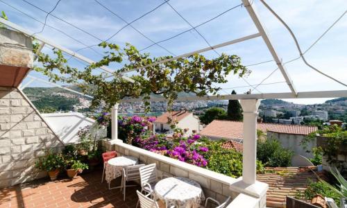 a balcony with tables and chairs and flowers at Guest House Misita in Dubrovnik
