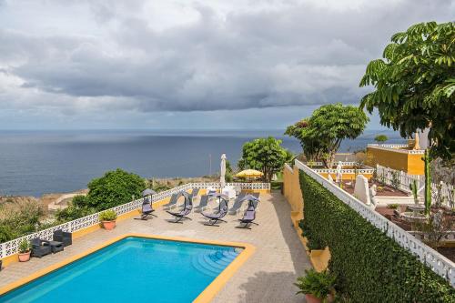 a swimming pool with chairs and the ocean in the background at Apartment La Gomera II in San Juan de la Rambla