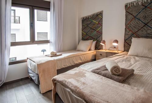 a bedroom with two beds and a window at Green View Luxury appartment in new complex Pueblo Majorero next to golf course 5 min walk from the Beach and Atlantico Shopping Centre in Caleta de Fuste Next to Cassino and Elba Sara Hotel 2 bedrooms 2 bathrooms huge terace! in Caleta De Fuste