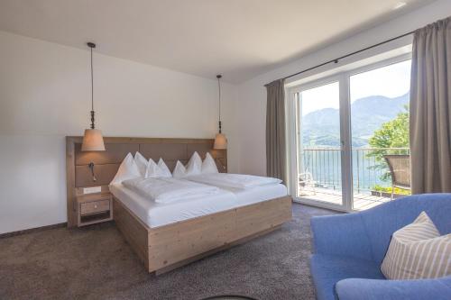 a bedroom with a bed and a couch and a window at Hotel Stadler am Attersee in Unterach am Attersee