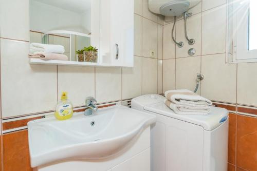 a bathroom with a sink and a washing machine at Apartment Angie - terrace with sea view in Nečujam