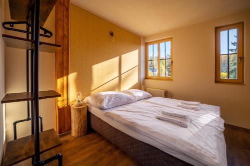 een slaapkamer met een bed met witte lakens en 2 ramen bij Valnovka Wellness Hotel in Kamenice