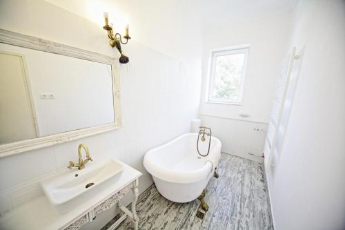 La salle de bains blanche est pourvue d'un lavabo et d'un miroir. dans l'établissement Levendula ház - Rosie Home, à Balatonlelle