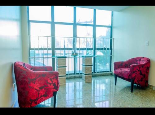 two chairs and a table in a room with a window at Crystal Plaza Hotel Marista in Goiânia