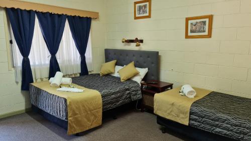 1 dormitorio con 2 camas y cortinas azules en Merriwa Motor Inn en Merriwa