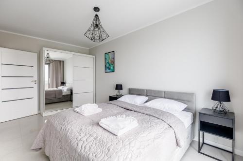 a white bedroom with a large bed and a mirror at Balticus Apartamenty Deluxe Promenada Gwiazd 14 in Międzyzdroje