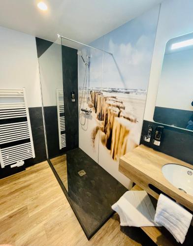 a bathroom with a sink and a shower with a picture of cows at Stadthotel-Garni Smutje in Norden