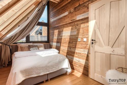 una camera con letto e parete in legno di Czarne Wierchy jacuzzi - Luxury Chalets Kościelisko a Kościelisko