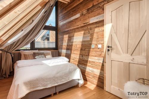 sypialnia z łóżkiem i drewnianą ścianą w obiekcie Czarne Wierchy jacuzzi - Luxury Chalets Kościelisko w mieście Kościelisko