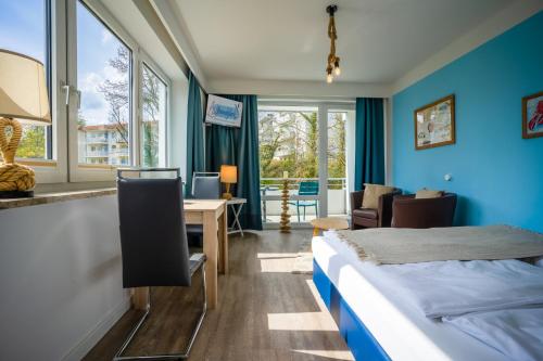 ein Hotelzimmer mit einem Bett, einem Schreibtisch und Fenstern in der Unterkunft Studio 31 "Strandgut" in Grömitz