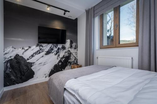 a bedroom with a bed and a tv on a wall at Villa 7 Apartments in Zakopane