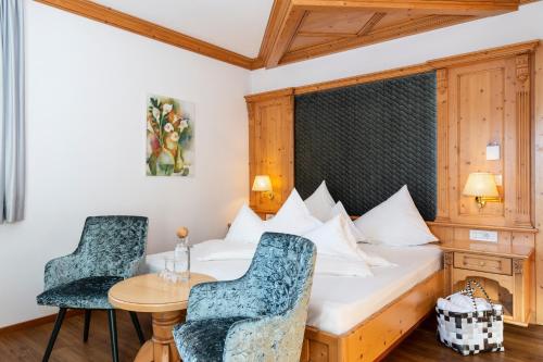 a bedroom with a bed and a table and chairs at Hotel Schlosswirt in Schenna