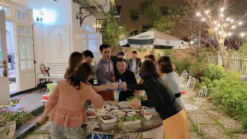 Un groupe de personnes autour d'une table avec de la nourriture dans l'établissement Villa Trung Nghĩa 30, à Đà Lạt