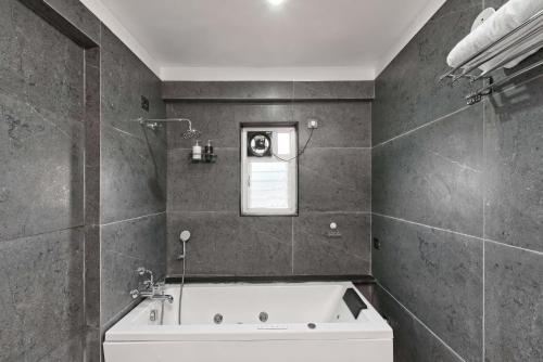a bathroom with a bath tub and a window at SaffronStays Riverdale, Mulshi - Lakefront villa with pool and mountain view in Pune