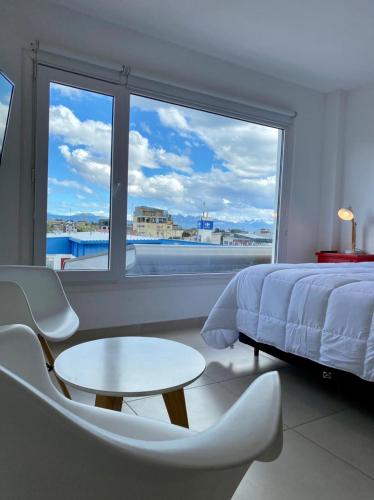a bedroom with a bed and a table and a large window at Penguins Flats 3 in Ushuaia