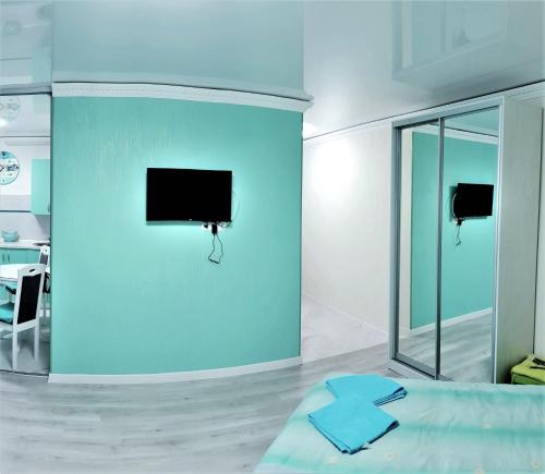 1 dormitorio con una pared azul y TV. en Апартаменти на центральному Кельнському бульварі, en Dnipro