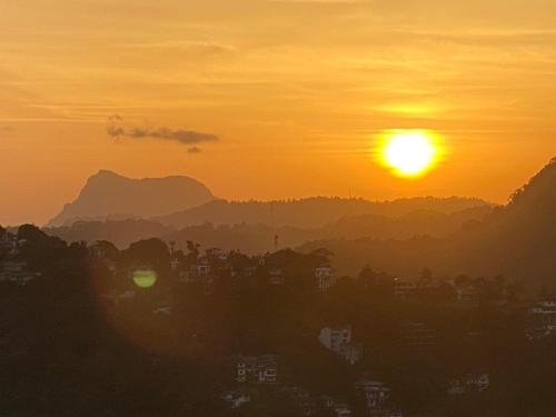 a sunset with the sun setting over a city at The Heaven's Villa Kandy in Kandy