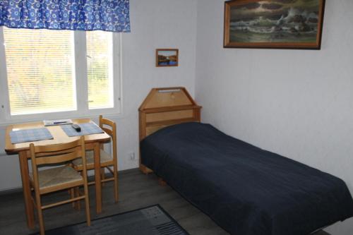 1 dormitorio con cama, escritorio y mesa en Ämmän Hotelli, en Suomussalmi
