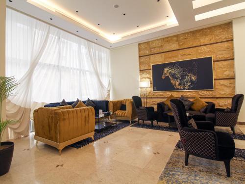 a lobby with couches and chairs and a large window at Friesian Hotel Suites in Jeddah