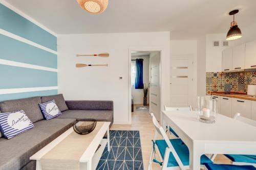 een woonkamer met een bank en een tafel bij Apartamenty Na Fali - Morski , Błękity , Marynarski in Pobierowo
