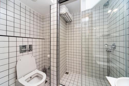 a white tiled bathroom with a toilet and a shower at Urban Park Hotels in Tbilisi City