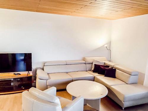 sala de estar con sofá, mesa y TV en Ferienwohnung - Schöne Aussicht, en Immenstaad am Bodensee