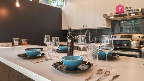 una cocina con una mesa con platos y copas de vino en The Marco-Polo of Portneuf - Open on nature - Private SPA Pool Sauna, en Pont-Rouge