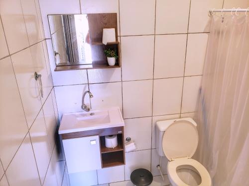 a small bathroom with a toilet and a sink at Pousada Aconchego in Peruíbe