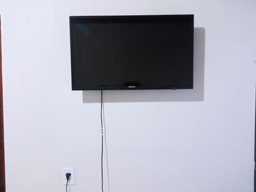 a flat screen tv hanging on a white wall at Suíte agradável no centro da cidade. in Boa Vista