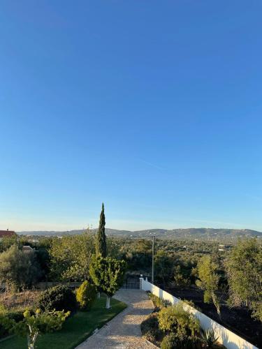 a path leading down to a field with trees and a fence at Casa Esperança - carefree living with big private pool and great views in Olhão