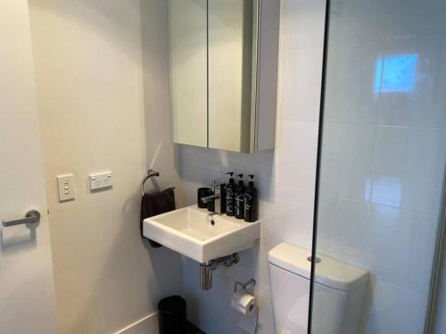 Baño blanco con lavabo y aseo en BEAUTIFUL CITY VIEWS CLOSE CITY AIRPORT FREE WINE en Perth