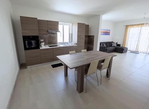 uma cozinha e sala de jantar com uma mesa de madeira e cadeiras em Close to Airport apartment em Żejtun