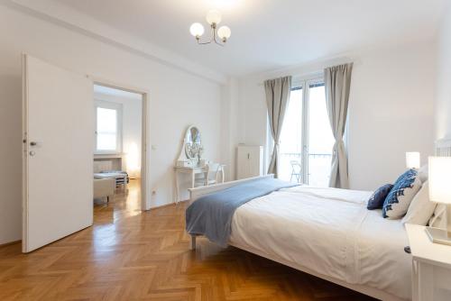 a white bedroom with a bed and a window at Operastreet City Center Santorin in Vienna