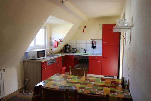 a kitchen with red cabinets and a table with chairs at Ferienwohnung Lahann in Saalfeld