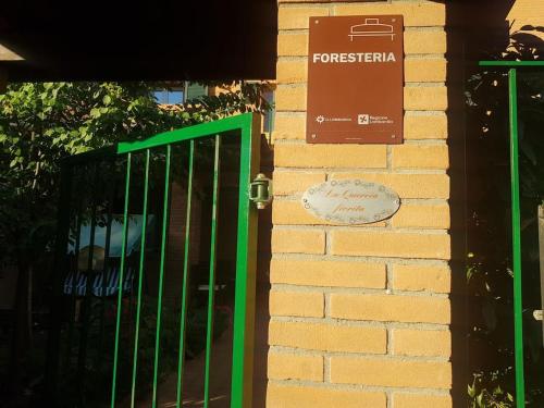 a green gate on a brick wall with a sign at La Quercia Fiorita in Trivolzio
