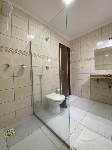 a bathroom with a toilet and a glass shower at Pousada das Palmeiras in Posse
